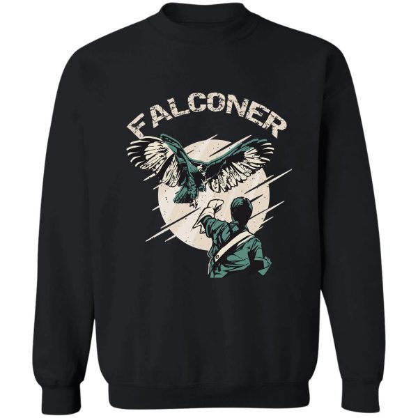 falconry bird landing on falconer arm sweatshirt